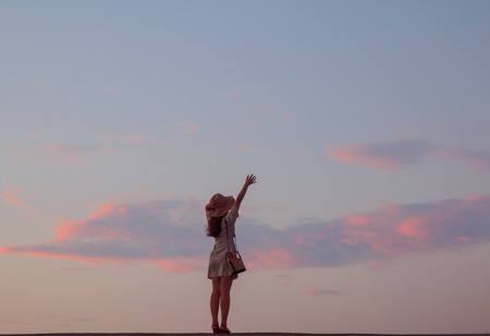 woman stretching her hand skyward in beautiful sunsetの写真素材