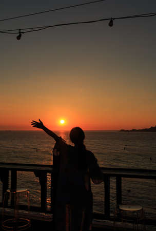 woman stretch her hand toward sun in the beautiful sunsetの写真素材