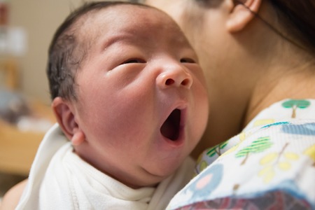 Asian new born baby yawning in mother's bosom