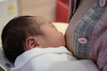 Asian baby is sucking at his mother's breast.の写真素材