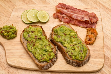 Guacamole with bread and avocado on wooden cutting boardの写真素材
