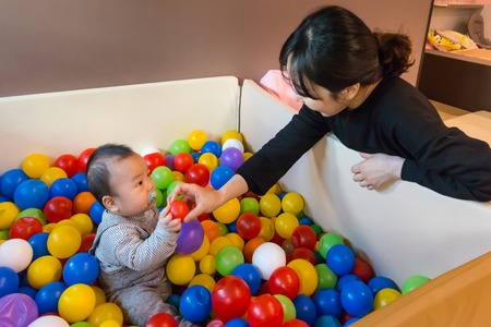 baby asian playing in colorful ball pool (ball pit)