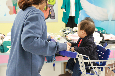 Asian mother and her baby boy shopping in clothing storeの写真素材