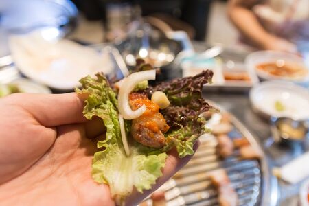 Korean BBQ, meat wrapped in lettuce on a hand