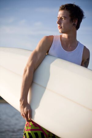 man at the beach holding his surfboard
