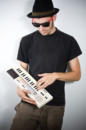 cool guy with hat playing on tiny keyboardの写真素材