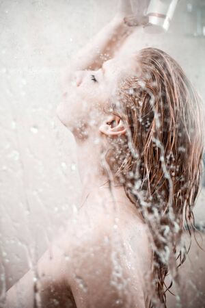 showering woman shot from behind glassの写真素材