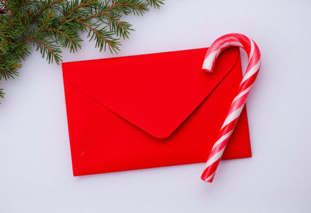 Red envelope with candy canes and fir branches on a white backgroundの素材