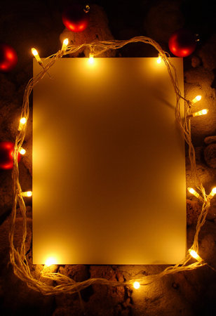 Blank sheet of paper with christmas lights on stone background.の素材