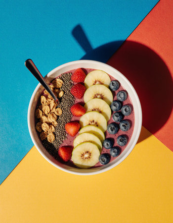 Healthy breakfast bowl with blueberry, apple, chia seeds and oatmeal on colorful backgroundの素材