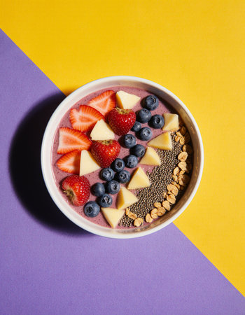 Healthy breakfast bowl with strawberry, blueberry, chia seeds and oatmeal on colorful backgroundの素材
