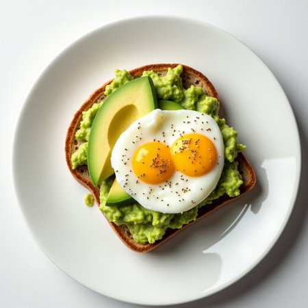 Avocado toast with fried egg and avocado on white plate, top viewの素材