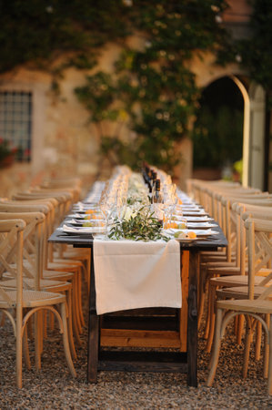 Outdoor summer wedding table set up with olive branches and linen cloths in a courtyard in Florence,Tuscany.の写真素材
