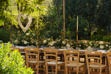 Rustic outdoor summer wedding table set up with green and cream floral decorations.の写真素材