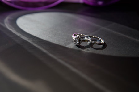 Close up of two wedding rings with a halo of light against black.の写真素材
