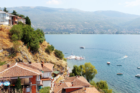 View of Ohrid Lake from above. Beautiful seascape with small boats. White houses with red roofs in the foreground. Mountains far away in the background. Photo taken in Ohrid, Republic of Macedoniaの写真素材