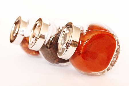 Three glass jars filled with spices isolated on white background. Paprika in the foreground.の写真素材