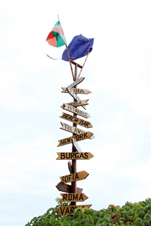 A wooden sign pointing in different destinations. Bulgarian and European Union flags on it. Photo...