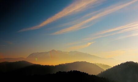 A very beautiful landscape with mountain tops. The sky, clouds and fog are colorful. The fog gives a deep of perspective.の写真素材