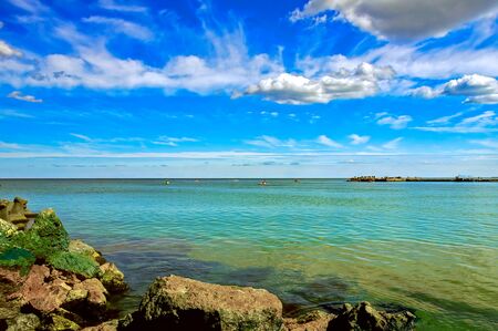 Seaside holiday. A lot of boats on the sea.  A fabulous sky like a painting.  The sea shore of large rocks.の写真素材