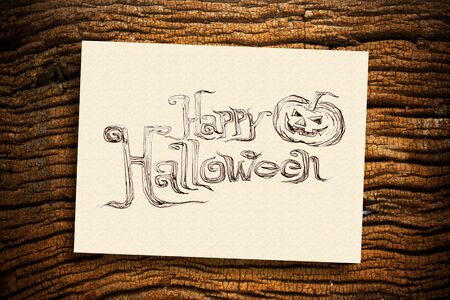 Hand writing "Halloween" on cream paper with ruin wood backgroundの写真素材