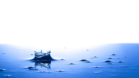 Splash crown shape of drop water in blue tone, blank space from above to create conceptual.の写真素材