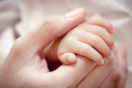 Close up and selective focus at fingers of baby newborn with hand of his mother.の写真素材