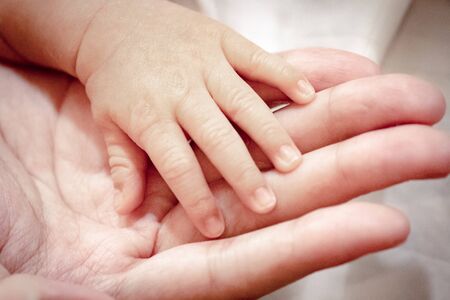 Close up and selective focus at fingers of baby newborn with hand of his mother.の写真素材