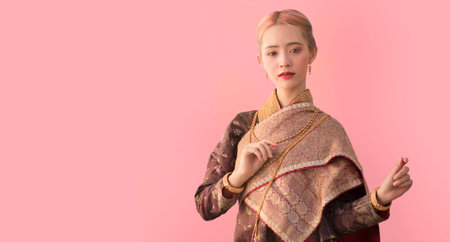 Portrait of a Thai woman wearing Thai traditional dress with pink background, as a guideline for...