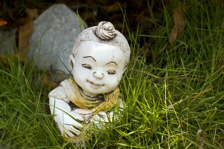 Child statue head in the grass.の写真素材