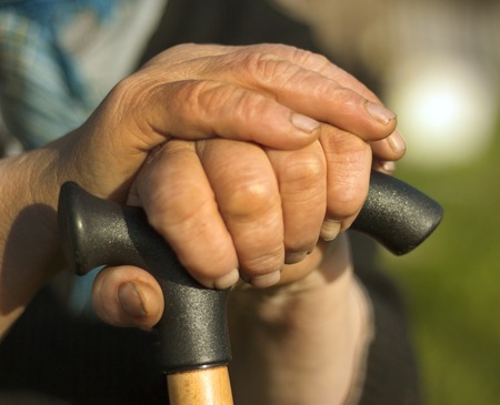 Closeup of senior woman's hands on wooden walking stickの写真素材