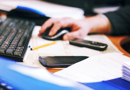 Selective focus-table: handwork, calculator, mobile phone, laptop and pen on a wooden table. Work in an office clerkの写真素材
