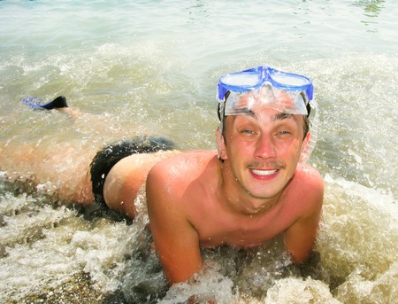 Hot Summer. The guy in blue glasses, in the sea is smiling at usの写真素材