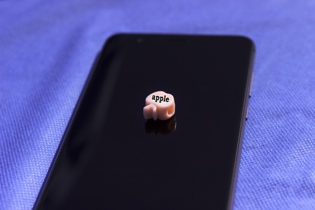 cellular telephone. An apple, a toy with an inscription. Close-up.