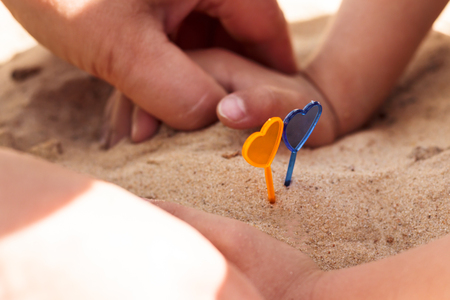Two hearts on a stick. Background sand beach. There are hands of the girl or without them.の写真素材