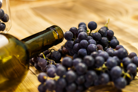 Image of a glass, freshly picked failed processing, black grapes on a wooden background and an empty bottle.の写真素材
