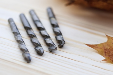 metal drill closeup on wooden background. close-up. there are maple leaves, no focus.の写真素材