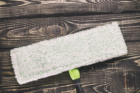 dark wooden background, mop and gloves. there is a scraper for glasses and cleaning products. there...