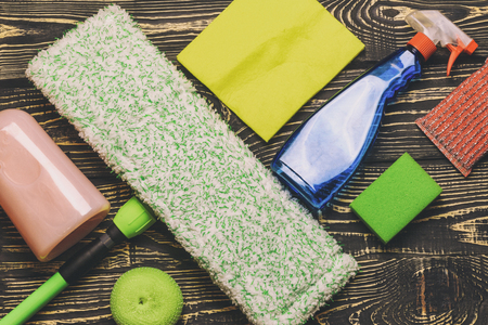 dark wooden background, mop and gloves. there is a scraper for glasses and cleaning products. there is tanirovanie.の写真素材