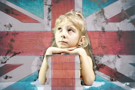 Little girl blonde, stack of books, flag of the United Kingdom, double exposure, there is toning.の写真素材