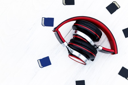 Wooden background in the old style. Musical accessories. headphones are red. memory card. have...