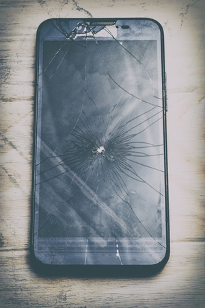 wooden background in retro style. The phone is broken glass in the center. have toning. close-up.の写真素材