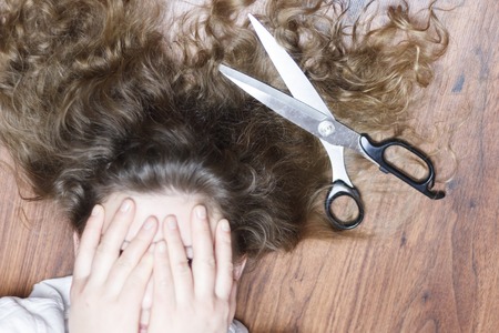 the girl covered her face with her hands. have scissors. The concept of haircut for sick hair, or...
