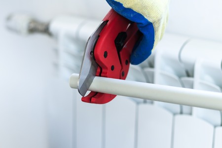man with red scissors cut pipes for heating, or water. polypropylene mounting system.