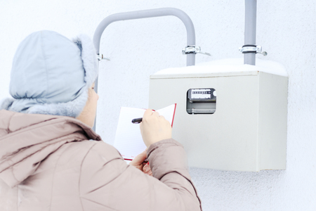 winter, snow, cold. the girl, the engineer, the worker records the readings of the sensors and pressure gauges. They are located on the street and located in a special box.の写真素材
