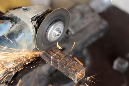 master using grinders. a lot of sparks burn and work. cuts a square pipe. have toning. close-up.