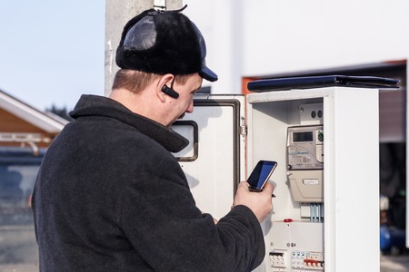 Minsk. Belarus. January 23, 2019. The owner of the house is checking the electricity meter on the street. Winter, a lot of snowのeditorial素材