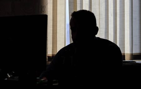 man sits in the office at the computer. only silhouette.の写真素材