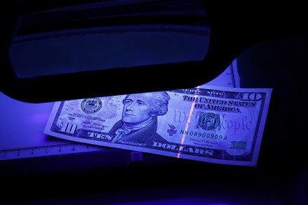 ten dollars on the photo. US banknotes. Equipment for in-depth inspection of money. Checking bills in ultraviolet light. Fake money or financial crisis conceptの写真素材