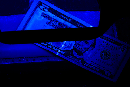 Five dollars in the photo. US banknotes. Equipment for in-depth inspection of money. Checking bills in ultraviolet light. Fake money or financial crisis conceptの写真素材
